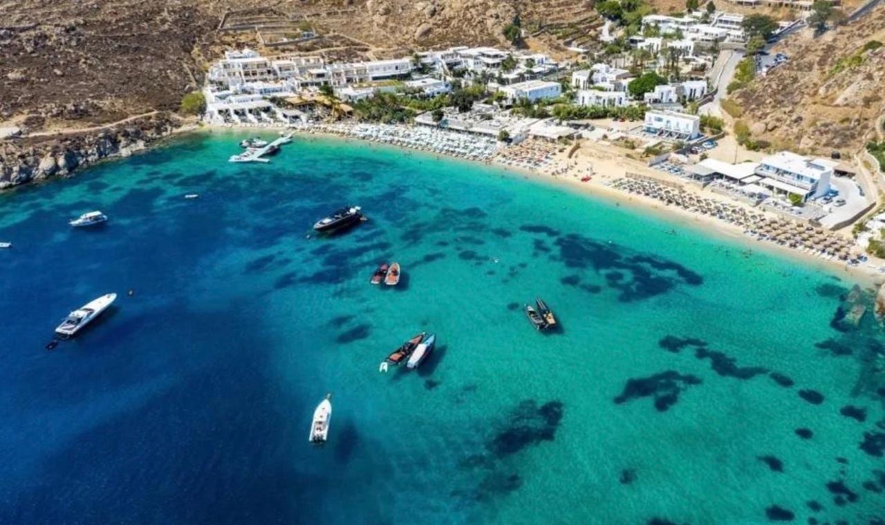 Yachts and speedboats anchored over the clear water of a southern Mykonos cove
