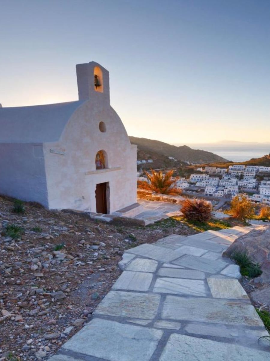 Golden-hour light over whitewashed Chora and its blue-domed church above the sea, Ios